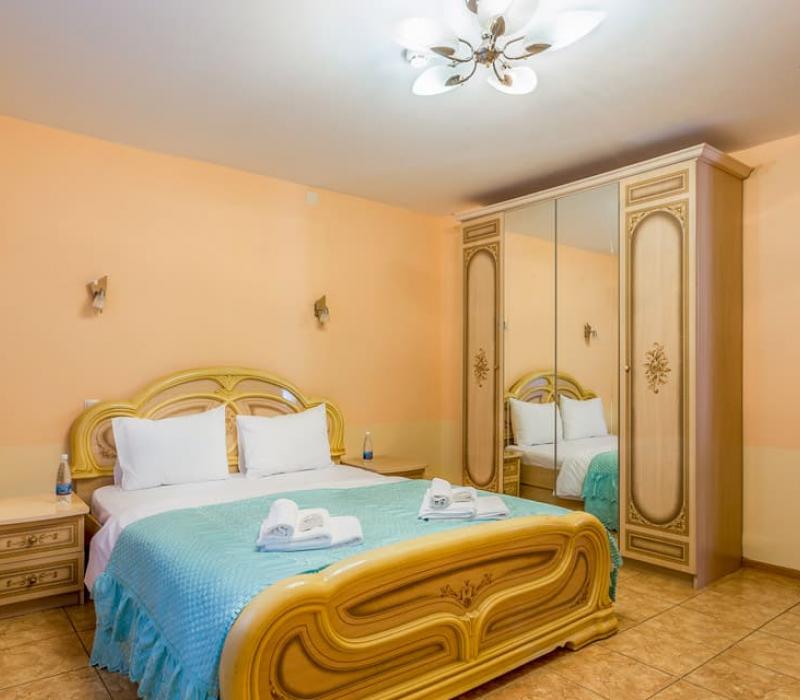 Двуспальная кровать в спальне в 4 местном 2 комнатном номере Семейный на первом этаже, Коттедж. СПА-отель Русский Дом Дивный 43°39° в городе Сочи